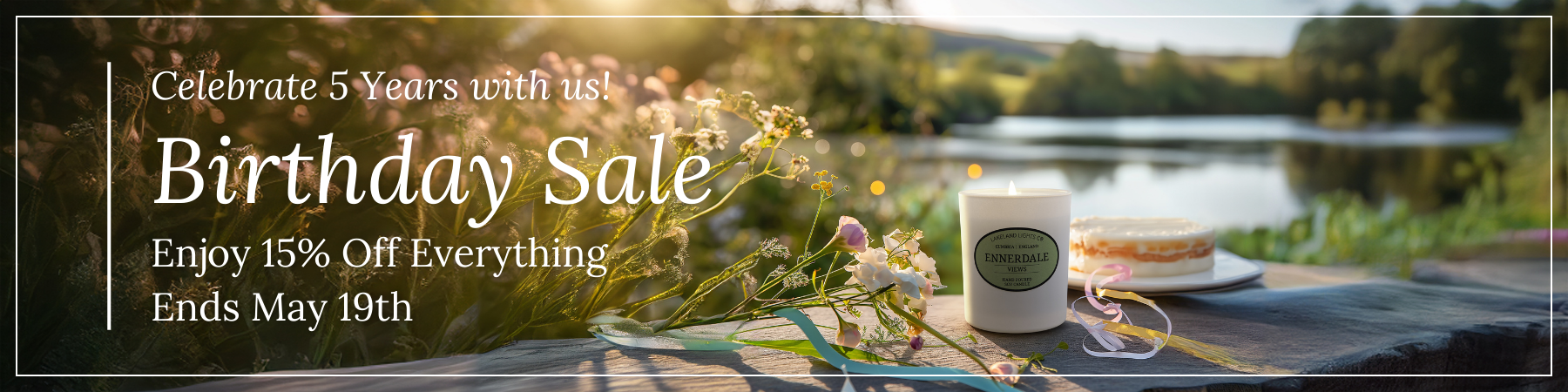 A Lakeland Lights luxury scented soy candle set in the beautiful Cumbrian scenery with a birthday cake behind to celebrate the company's 5th birthday. Text announces a sale lasting until 19th May with 15% off everything on the website