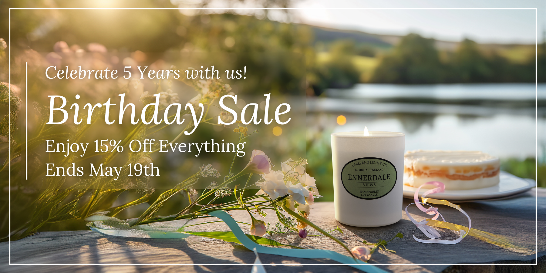 A Lakeland Lights luxury scented soy candle set in the beautiful Cumbrian scenery with a birthday cake behind to celebrate the company's 5th birthday. Text announces a sale lasting until 19th May with 15% off everything on the website