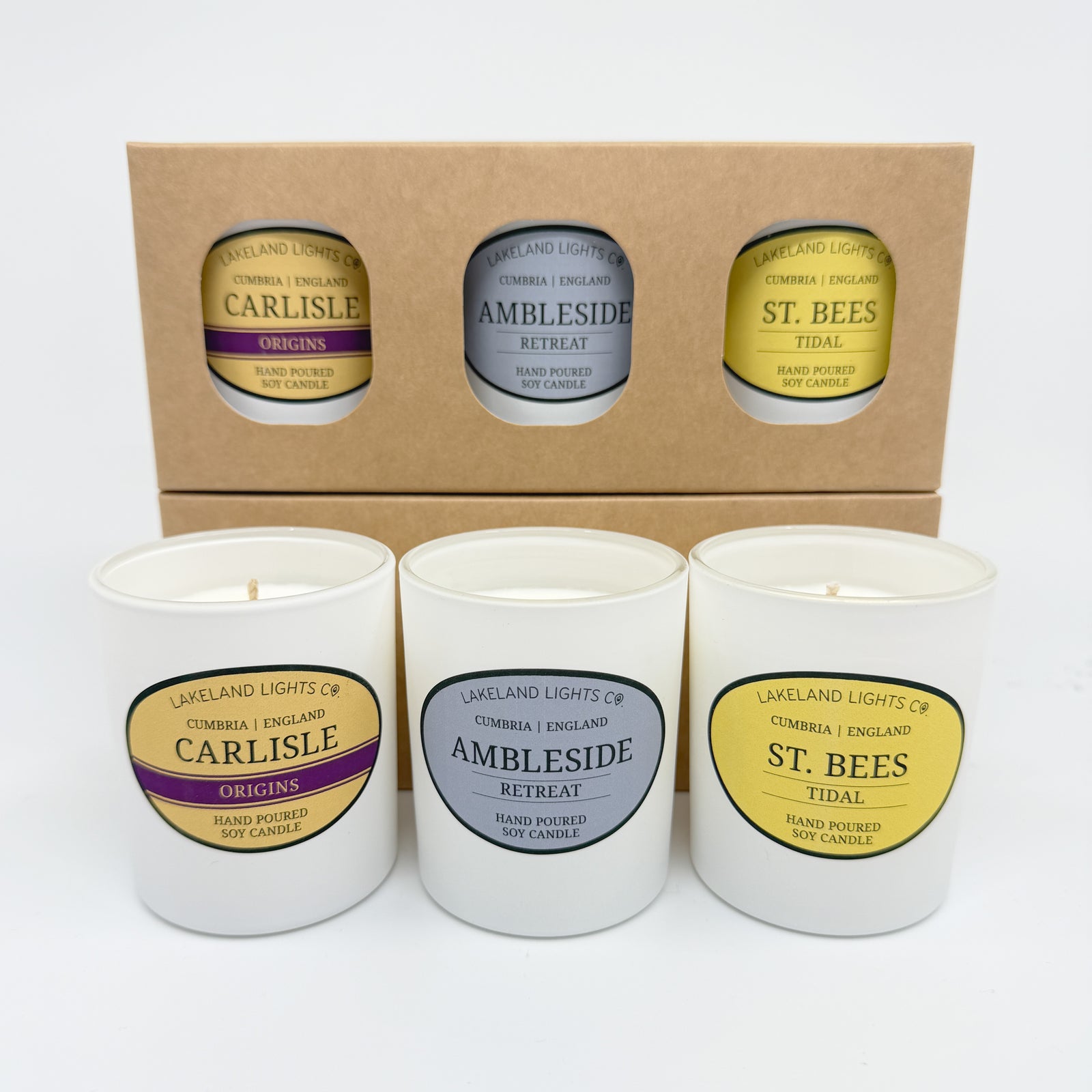 Three candles with labels on a wooden surface with a neutral background
