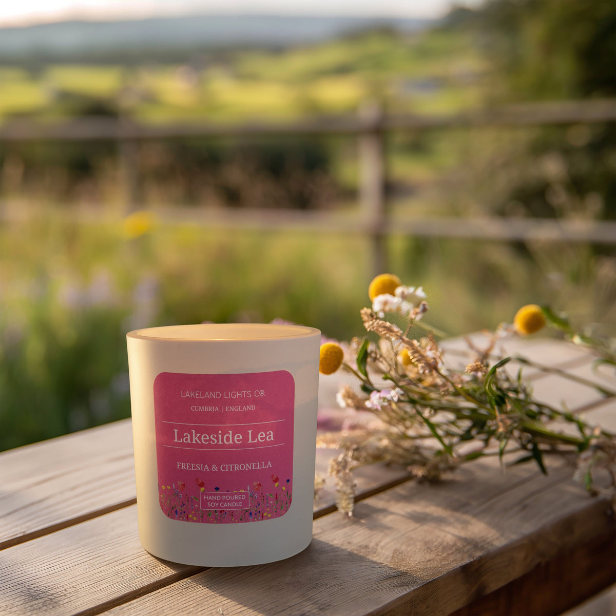 Lakeside Lea soy candle by Lakeland Lights, featuring freesia and citronella scent outside in a summer setting